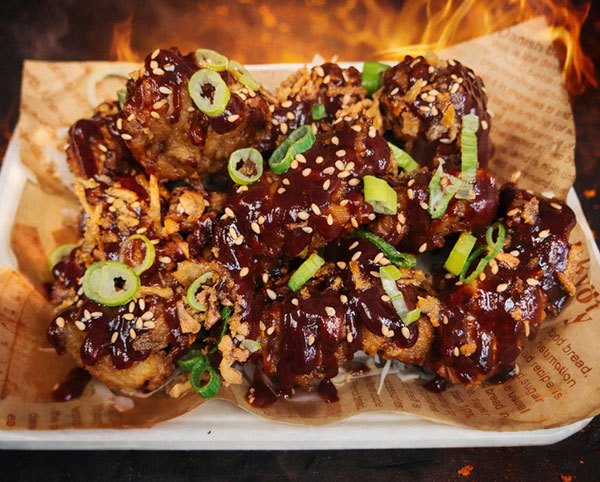 Korean-style fried chicken wings tossed in sticky red sauce with sesame seeds